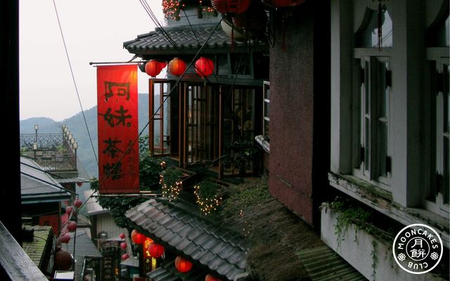 A vertical red banner declaring 阿妹茶樓 hanging beside a multistorey traditional Chinese building
